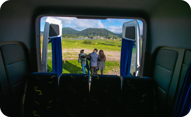 Van vista de adentro hacia afuera llegando de un viaje, afuera se ven 3 turistas.