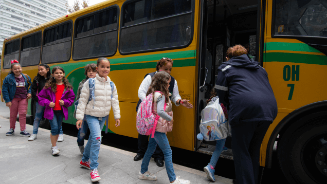 Niños en fila subiendo a un transporte escolar.